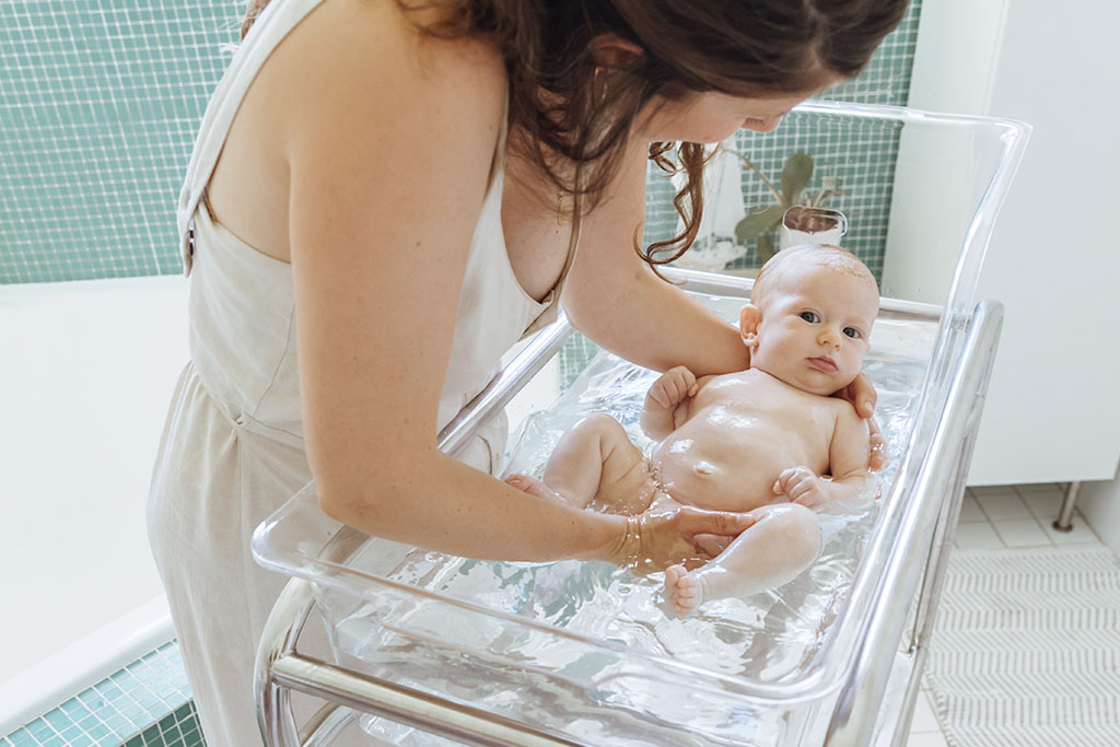 Mum bathes baby in bassinet